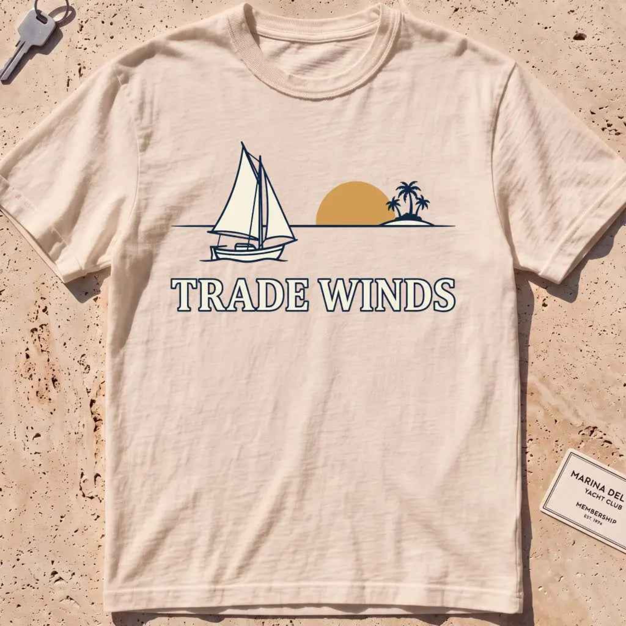 ivory heavyweight tee with a sailboat, sun and palms "Trade Winds" graphic.