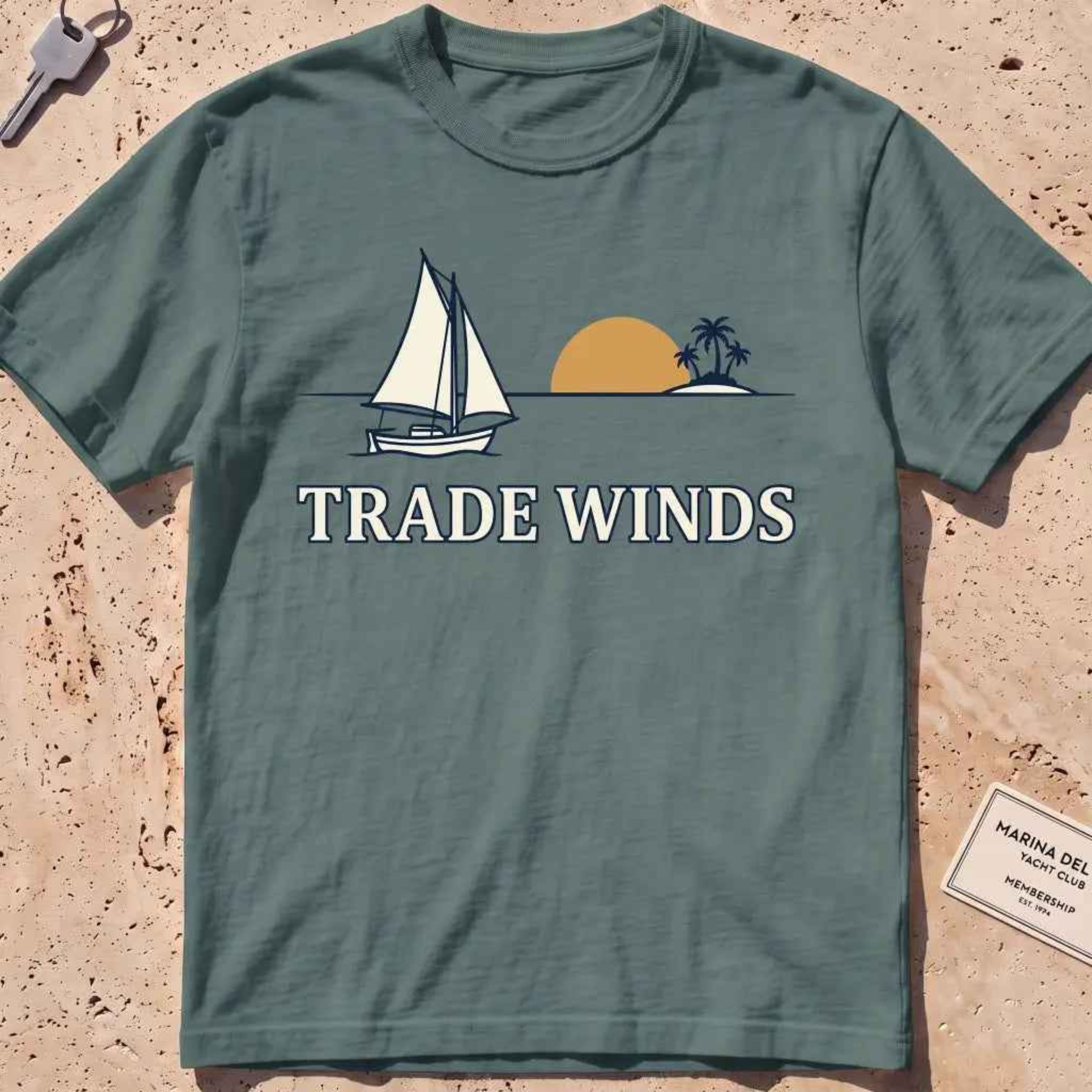 blue spruce heavyweight tee with a sailboat, sun and palms "Trade Winds" graphic.